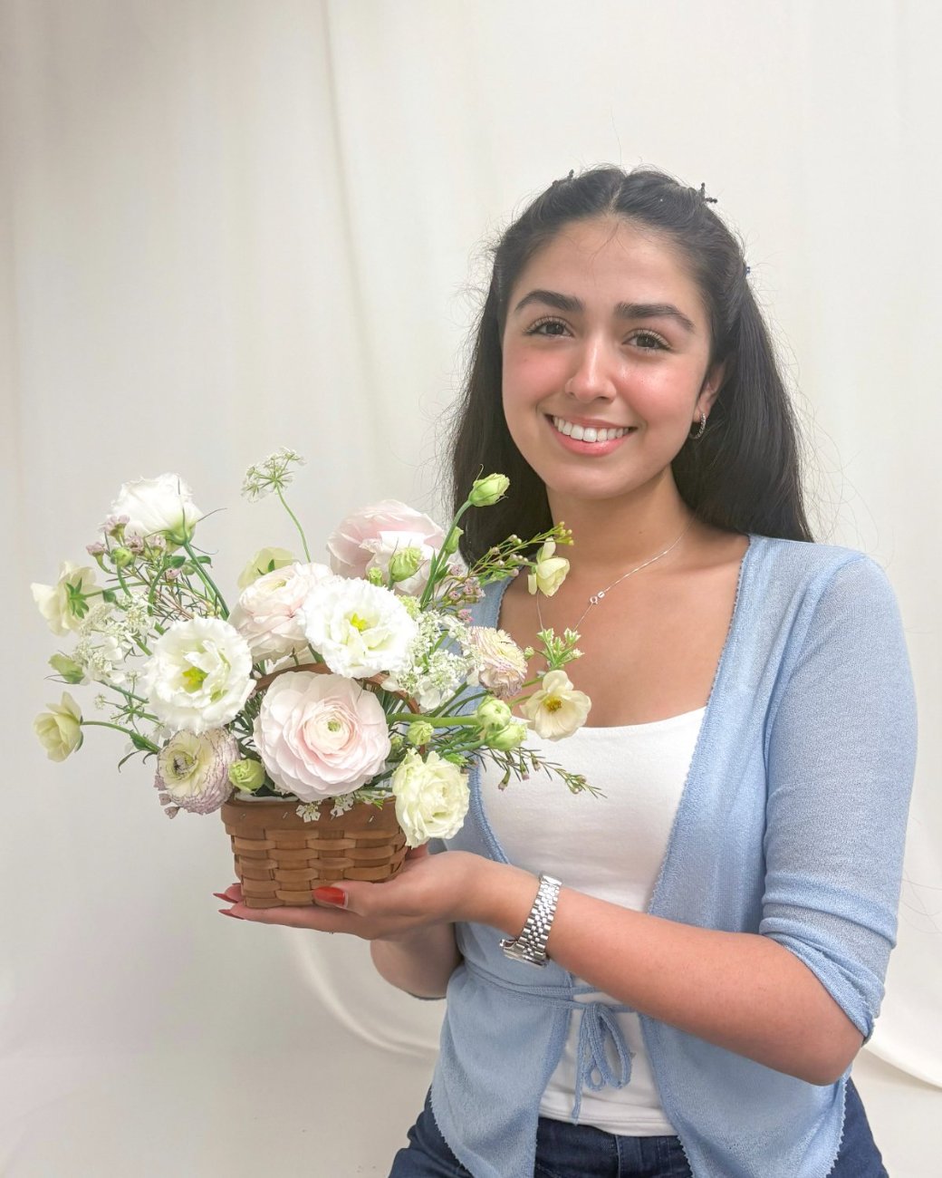 Daniela, smiling, holding a Basket of ranunculus and lisianthus